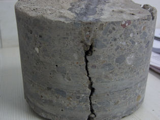 A concrete screed has cracked beneath a saw cut joint, which was subsequently filled with sealant at the surface.